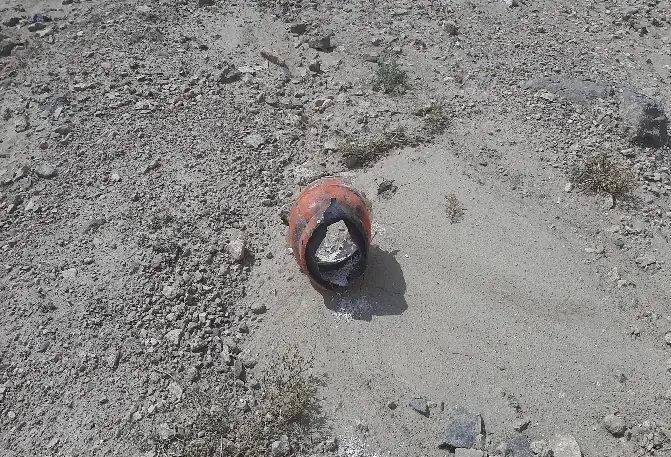 The same canister after disposal, blackened and split open on the ground.